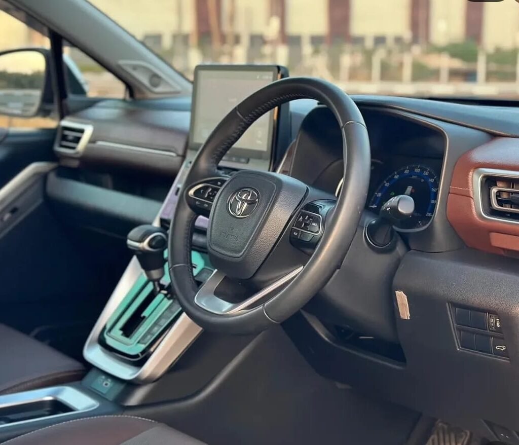 Premium interior of the Toyota Innova Hycross featuring a multifunction steering wheel, touchscreen infotainment system, automatic gear selector, and modern dashboard.