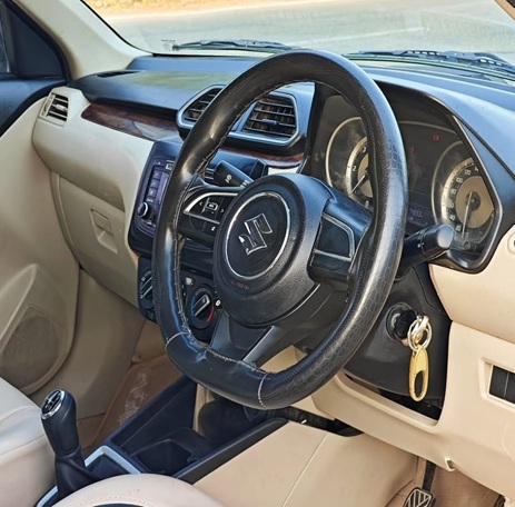 Maruti Suzuki Swift Dzire steering wheel and driver cockpit with clean dashboard and manual transmission by Limo Car India.